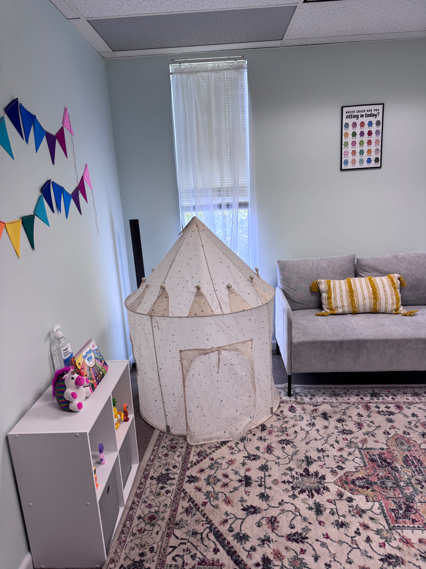 Play area with a canvas tent, toy shelf, and colorful bunting